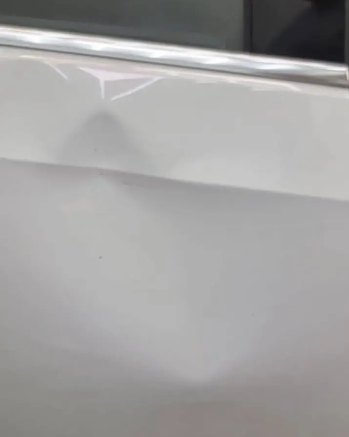 Before: Dent low on a white door